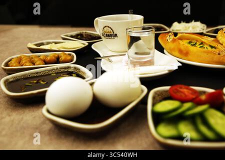 Frühstückstisch aus dem Nahen Osten mit frischem Gemüse, gekochten Eiern, Dattelobst, Labneh-Bällchen in Olivenöl, Melasse-Marmelade und frisch gebackenem Käse Stockfoto