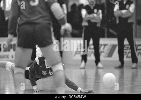 Volleyball Tschechen + Ostdeutsche, Volleyball, 29-03-1990 Whizgle News, Dutch Desk, Niederlande, 1950-2000 Ein Spieler taucht zum Boden und greift während eines intensiven Volleyballspiels nach dem Ball, während Teamkollegen und Trainer aufmerksam aus dem Hintergrund beobachten. Die Szene zeigt den Fokus und die Entschlossenheit der beteiligten Athleten. Stockfoto