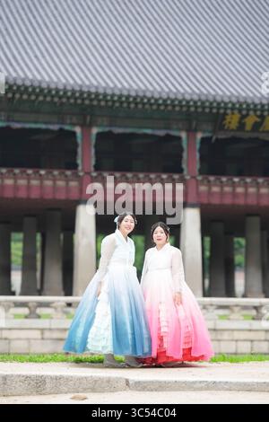 Im Juni posierten in Seoul zwei koreanische Frauen in ihren Zwanzigern vor einem historischen Saal im Gyeongbokgung Palace, in süßem rosa und himmelblauem hanbo Stockfoto