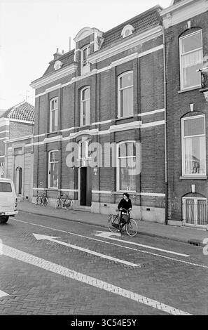 Erw. Jugendzentrum d'Appelaer, externes Jugendzentrum, Kampersingel, externe Garage, Amsterdamsevaart, Außenansicht, Haarlem, Amsterdamsevaart, Niederlande, 22-03-1972 Whizgle News, Dutch Desk, Niederlande, 1950-2000 Ein Radfahrer hält auf einer kopfsteingepflasterten Straße vor einem prächtigen Backsteingebäude mit großen Fenstern. Fahrräder stehen in der Nähe, und die Szene spiegelt eine ruhige, urbane Atmosphäre wider. Stockfoto