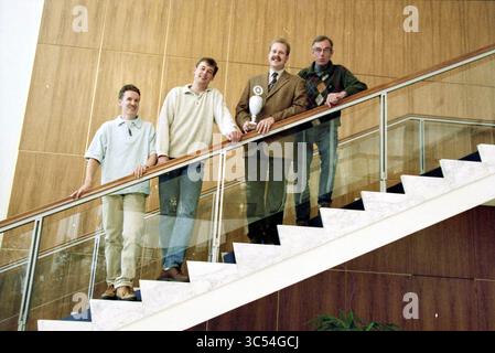 Sports Champions 1999, IJmuiden, IJmuiden, Niederlande, 28-05-2000 Whizgle News, Dutch Desk, Niederlande, 1950-2000 Eine Gruppe von vier Personen steht auf einer Treppe, lächelt und posiert zusammen. Eine Person hält eine Trophäe, während die anderen lässig stehen und eine Mischung aus lässiger und formeller Kleidung zeigen. Die Einrichtung verfügt über eine moderne Inneneinrichtung mit Holztäfelung und einem stilvollen Geländer. Stockfoto