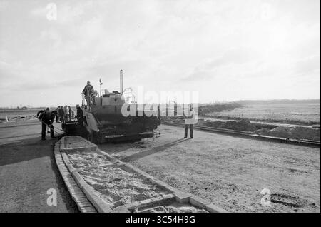 Straßenbau, neuer Straßenbau Waarderpolder., Straßen, Straßenbau, Straßenbau, Straßenbau, 27-11-1986 Whizgle News, Dutch Desk, Niederlande, 1950-2000 Arbeiter arbeiten mit schweren Maschinen, während sie eine Straße pflastern. Die Szene fängt einen Moment der Bautätigkeit ein und zeigt sowohl die Maschinen als auch die Arbeiter, die am Prozess beteiligt sind. Stockfoto