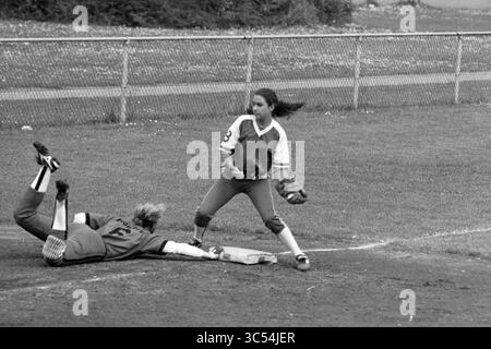 Softball, Pioneers - HVV, 08-06-1991 Whizgle News, Dutch Desk, Niederlande, 1950-2000 Ein Spieler rutscht in die Basis, während ein anderer Spieler, bereit und bereit, den Ball zu werfen vorbereitet. Die Intensität des Spiels ist spürbar, da sich beide Athleten auf das Spiel konzentrieren. Stockfoto