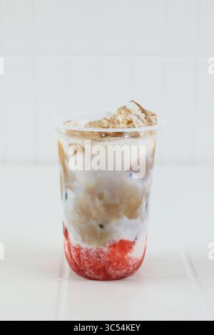 Ein Glas Eiskaffee Latte mit Erdbeermarmelade auf Plastikbecher zum Mitnehmen Stockfoto