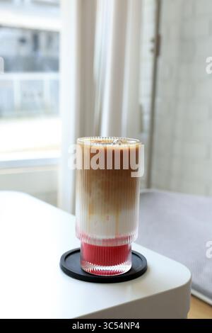 Ein Glas Eiskaffee Latte mit Erdbeermarmelade in einem gemütlichen Café Stockfoto