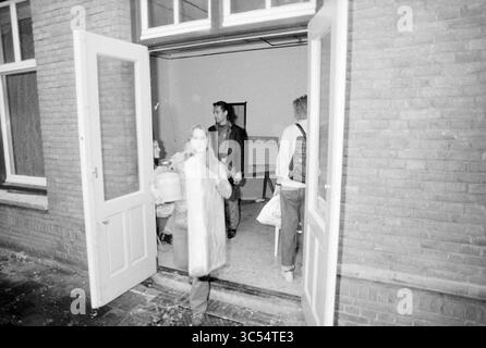 Marinekrankenhaus besetzte, 14-09-1991 Whizgle News, Dutch Desk, Niederlande, 1950-2000 Eine Gruppe von Menschen wird durch eine von Ziegelwänden eingerahmte Tür in einen Raum hinein- und wieder verlassen. Eine Person trägt einen großen Container, während eine andere in der Nähe des Eingangs steht, und ein drittes ist teilweise im Hintergrund sichtbar, was eine offene Szene des täglichen Lebens schafft. Stockfoto