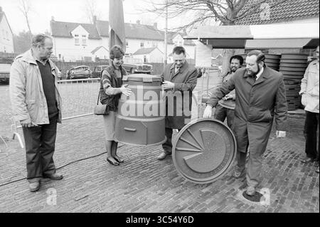 Erster Kompostbehälter für den Rat von Bloemendaal, Verschiedenes, Gärten und Parks, Bloemendaal, 17-04-1988 Whizgle News, Dutch Desk, Niederlande, 1950-2000 Eine Gruppe von fünf Personen versammelt sich um ein großes, zylindrisches Objekt, das von zwei Männern und einer Frau getragen wird. Die Szene scheint draußen zu sein, mit Gebäuden im Hintergrund und mehreren runden Deckeln auf dem Boden. Die Einzelpersonen arbeiten an einer gemeinsamen Arbeit und schlagen eine Demonstration oder Installation in Bezug auf das Objekt vor. Stockfoto