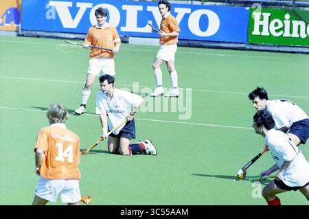 Hockeyspiel Bloemendaal-Amsterdam, 01-04-1995 Whizgle News, Dutch Desk, Niederlande, 1950-2000 Eine Gruppe von Feldhockeyspielern, die an einem Wettkampf teilnahmen und verschiedene Fähigkeiten und Taktiken zeigten. Ein Spieler kniet in den Vordergrund, während andere bereit sind, Action zu erleben, mit lebhaften Teamtrikots, die sich von der Spielfläche abheben. Werbebanner sind im Hintergrund sichtbar und tragen so zur dynamischen Atmosphäre des Spiels bei. Stockfoto