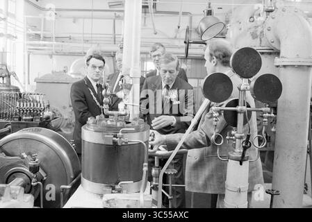 Eröffnung der Dampfpumpenstation auf halbem Weg durch Prince Claus, Eröffnung, Eröffnung, Inbetriebnahme, Dampfpumpenstation und Dampfpumpenstation, Halfweg, 10-06-1987 Whizgle News, Dutch Desk, Niederlande, 1950-2000 Eine Gruppe von Männern in formeller Kleidung spricht über Maschinen und Geräte in einer Fabrikumgebung, umgeben von verschiedenen industriellen Bauteilen und Rohren. Einige Teilnehmer tragen Blumenkorsagen, die auf einen besonderen Anlass oder eine besondere Veranstaltung hinweisen. Stockfoto