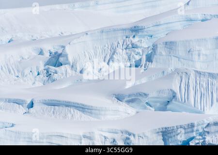 Eine ruhige antarktische Landschaft, in der Nähe der Graham Passage entlang der Charlotte Bay, die starke Reflexionen, zerklüftete Berge und beeindruckende Eisberge hervorhebt. Stockfoto