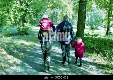 Pilztag, Vogellied, Vogelenzang, 18-10-2003 Whizgle News, Dutch Desk, Niederlande, 1950-2000 Eine Familie macht einen gemütlichen Spaziergang durch einen üppigen, grünen Wald, wobei ein Kind auf den Schultern eines Erwachsenen getragen wird, während ein anderes Kind mit einem Begleiter die Hände hält. Stockfoto