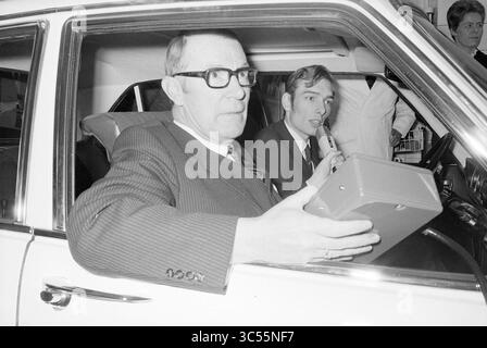 Eröffnung Tankstelle Gesamt, Eröffnung, Öffnungen, Inbetriebnahme, Gesamt, Haarlem, Friese Varkenmarkt, Niederlande, 28-03-1969 Whizgle News, Dutch Desk, Niederlande, 1950-2000 Ein Mann in Anzug und Brille sitzt in einem Auto, hält ein kleines Gerät, während er mit einem anderen Mann neben ihm spricht, der ebenfalls in einem Gespräch ist. Die Szene nimmt einen Moment der Diskussion oder Demonstration auf, der wahrscheinlich Technologie oder Kommunikation betrifft. Stockfoto