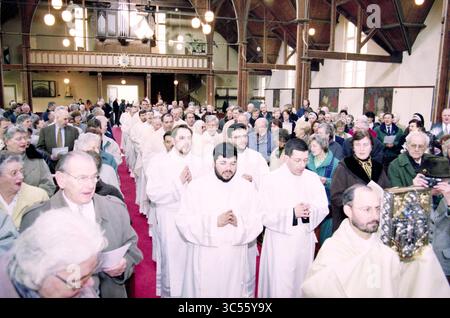 Ordination von vier Diakonen, Heiloo, Heiloo, 24-03-1999 Whizgle News, niederländisches Büro, Niederlande, 1950-2000 Eine Menschenmenge versammelt sich in einer Kirche, mit Priestern in weißen Gewändern, die die Prozession leiten. Die Atmosphäre ist eine Atmosphäre der Ehrfurcht, da die Teilnehmer in formeller Kleidung eine Mischung von Emotionen zeigen, die von Freude bis zu feierlichem Anlass reichen. Die architektonischen Details und die Beleuchtung verbessern die spirituelle Atmosphäre der Versammlung. Stockfoto