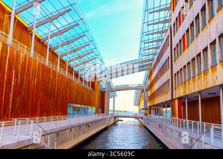 Moderne Architektur im Aker Brygge in Oslo, elegante Holzgebäude mit glasüberdachten Gängen über den Kanal. Design vereint urbane Raffinesse Stockfoto
