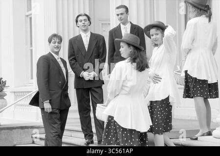 Blumenjungen in BL'daal, Bloemendaal, 18-03-1991 Whizgle News, Dutch Desk, Niederlande, 1950-2000 Eine Gruppe elegant gekleideter Individuen steht auf einer Treppe, die sich unterhalten und lachen. Einige tragen stilvolle Hüte, andere tragen Blumenmuster auf ihrer Kleidung, was eine charmante, soziale Atmosphäre schafft. Im Hintergrund befindet sich ein elegantes Gebäude, das das Gefühl der Raffinesse noch verstärkt. Stockfoto