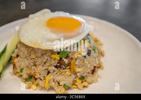 Das ist ein Teller mit gebratenem Reis, belegt mit einem Ei mit sonnigen Seiten. Stockfoto