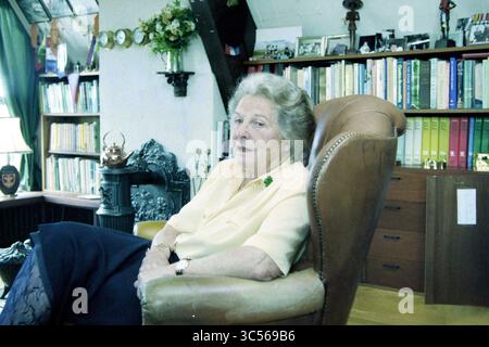 Innenraum Wohnzimmer mit Dame im Sessel, 00-00-1998 Whizgle News, Dutch Desk, Niederlande, 1950-2000 eine ältere Frau sitzt bequem in einem gemütlichen Sessel, umgeben von Büchern und persönlichen Gegenständen, die Geschichten über ihr Leben erzählen. Sie trägt eine hellgelbe Bluse und einen zufriedenen Ausdruck, der der einladenden Atmosphäre des Raumes Wärme verleiht. Stockfoto