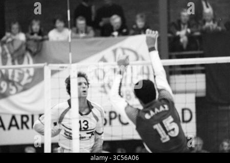 Volleyturnier, Menschenmassen, Volleyball, 18-12-1988 Whizgle News, Dutch Desk, Niederlande, 1950-2000 Ein angespannter Moment fängt zwei Volleyballspieler in Aktion, wobei einer sich darauf vorbereitet, den Ball über das Netz zu werfen, während der andere bereit ist, den Ball zu blockieren. Die Zuschauer jubeln im Hintergrund und schaffen eine elektrisierende Atmosphäre. Stockfoto
