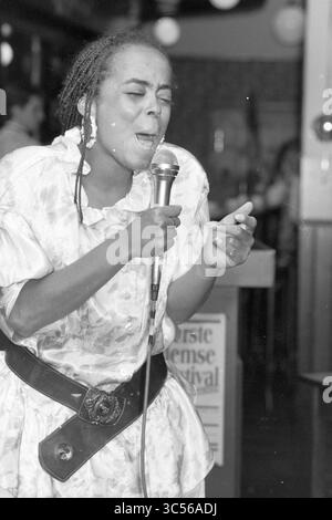Gesangsfestival in Zijlpoort, Gesangschöre und Gesangschöre, 01-05-1988 Whizgle News, Dutch Desk, Niederlande, 1950-2000 Eine Frau singt leidenschaftlich in ein Mikrofon, ihr Ausdruck erfüllt von Emotionen, während sie auf der Bühne auftritt. Sie trägt ein helles, fließendes Kleid und einen stilvollen Gürtel, der das Publikum mit ihrer starken Präsenz in ihren Bann zieht. Stockfoto