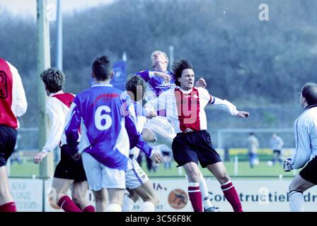 Fußball: Stormvogels - DCO, IJmuiden, IJmuiden, Niederlande, 08-03-2003 Whizgle News, Dutch Desk, Niederlande, 1950-2000 Eine Gruppe von Fußballspielern hat während eines Spiels einen intensiven Moment, wobei ein Spieler hoch über die anderen springt und versucht, den Ball zu führen. Die Szene fängt die Energie und den Wettkampfgeist des Spiels ein, während die Spieler in kontrastierenden Trikots um die Position justieren. Stockfoto