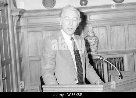 Installation von Bürgermeister Machielsen Zandvoort, Bürgermeister, 05-10-1977 Whizgle News, Dutch Desk, Niederlande, 1950-2000 Ein Mann steht auf einem Podium und spricht mit selbstbewusstem Ausdruck vor einem Publikum. Er trägt einen Anzug und Krawatte, mit einer Holzkulisse mit klassischen architektonischen Details. Eine dekorative Vase ist auf einem Regal hinter ihm zu sehen, was die formelle Umgebung noch unterstreicht. Stockfoto