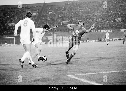 Football Amsterdam 701, Anderlecht - Leeds United, Football, 06-08-1976 Whizgle News, Dutch Desk, Niederlande, 1950-2000 Ein dynamisches Fußballspiel in vollem Gange, bei dem ein Spieler einem Gegner gekonnt ausweichen kann, während sich ein anderer Teamkollege darauf vorbereitet, zu helfen. Die Intensität des Spiels ist spürbar, da die Zuschauer den Hintergrund füllen und die Action beobachten. Stockfoto