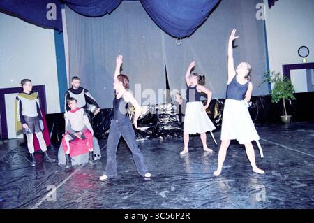 Theatervorstellung Coornhert Lyceum, Haarlem, Niederlande, 27-01-2000 Whizgle News, Dutch Desk, Niederlande, 1950-2000 Eine dynamische Performance mit Tänzern in verschiedenen Posen, die eine Mischung aus Bewegung und Ausdruck zeigt. Einige Darsteller tragen Kostüme, die ein Theaterthema vermuten lassen, während andere einfache Kleidung tragen, die zu einer einnehmenden und künstlerischen Atmosphäre beiträgt. Der Hintergrund ist minimalistisch und konzentriert die Aufmerksamkeit auf die Darsteller und ihren kreativen Ausdruck. Stockfoto