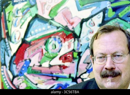 Mr. Labberton, Santpoort, Santpoort, 20-12-1999 Whizgle News, Dutch Desk, Niederlande, 1950-2000 Ein Mann mit Brille lächelt leicht im Vordergrund, während ein abstraktes, farbenfrohes Kunstwerk mit wirbelnden Formen und leuchtenden Farben den Hintergrund füllt. Stockfoto
