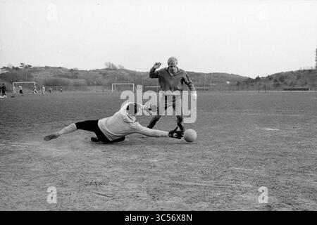 Jos Bakker, Stormvogels, Football People and Trainer, IJmuiden, Nederland, 19-04-1984 Whizgle News, Dutch Desk, Niederlande, 1950-2000 Ein Torwart macht einen verzweifelten Sturz, um einen Schuss zu blockieren, während ein Vorwärtsspieler den Ball in einem dynamischen Moment eines Fußballspiels geschickt manövriert und dabei Athletik und Teamwork auf dem Spielfeld zum Ausdruck bringt. Stockfoto