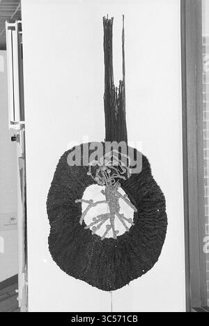 'Ausstellung 'Herbstfeeling', Wandteppiche + Keramik, Kulturzentrum, Z'voort', Ausstellung, 25-10-1977 Whizgle News, Dutch Desk, Niederlande, 1950-2000 ein abstraktes Textilkunstwerk mit kreisförmiger zentraler Form mit komplizierten Texturen und Mustern, umgeben von langen, fließenden Strängen, die sich nach oben erstrecken und einen auffälligen visuellen Kontrast bilden. Das Design vermittelt ein Gefühl organischer Bewegung und Tiefe. Stockfoto