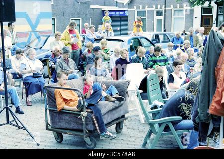 Rosa King, Heemstede, Heemstede, Niederlande, 28-06-1997 Whizgle News, Dutch Desk, Niederlande, 1950-2000 im Freien versammeln sich verschiedene Leute, die in verschiedenen Stühlen und auf einer Couch sitzen. Menschen jeden Alters sind aktiv, lesen etwas oder schauen intensiv nach vorne. Die Szene fängt ein lebhaftes Gemeindeevent mit farbenfroher Kleidung und Ausdrücken der Neugier und des Vergnügens ein. Im Hintergrund ist eine Gruppe von Künstlern zu sehen, die die festliche Atmosphäre verstärken. Stockfoto