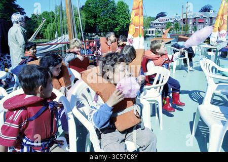 Ankunft geistig behinderter Kinder, 29-05-1997 Whizgle News, Dutch Desk, Niederlande, 1950-2000 Eine Gruppe von Kindern, die Schwimmwesten tragen, genießt einen unterhaltsamen Tag auf einem Boot, bei einigen leckeren flauschigen Baumwollbonbons. Lachen und Aufregung erfüllen die Luft, während sie die sonnige Umgebung und die lebendige Atmosphäre genießen. Stockfoto