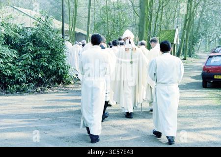 Ordination von vier Diakonen, Heiloo, Heiloo, 24-03-1999 Whizgle News, niederländisches Büro, Niederlande, 1950-2000 Eine Gruppe von Individuen in weißen Gewändern durchläuft ein bewaldetes Gebiet und nimmt möglicherweise an einer religiösen Zeremonie Teil. Die Atmosphäre ist ruhig, Bäume säumen den Weg und ein Gebäude im Hintergrund sichtbar. Stockfoto