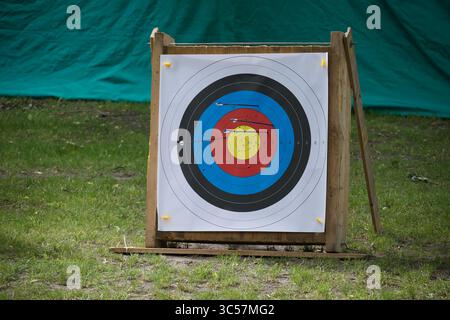 Bogenschießen zielt draußen ab und zeigt mehrere Pfeile, die im Bullseye und in der Umgebung getroffen wurden. Stockfoto