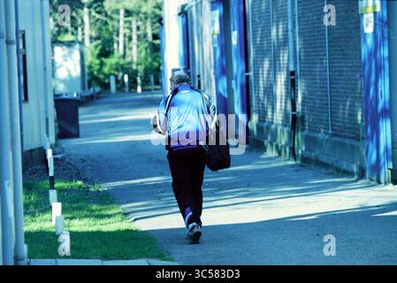 Simon Kistemaker, Velsen, Velsen, 27-10-1999 Whizgle News, Dutch Desk, Niederlande, 1950-2000 Eine Einzelfigur spaziert auf einem von Gebäuden gesäumten Weg, gekleidet in eine sportliche Jacke und trägt eine Tasche, während das Licht durch die Bäume in der Nähe fließt. Stockfoto