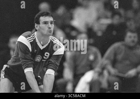 Volleyball Tschechen + Ostdeutsche, Volleyball, 29-03-1990 Whizgle News, Dutch Desk, Niederlande, 1950-2000 Ein männlicher Athlet in Aktion während eines Handballspiels, der ein Trikot mit der Nummer 9 trägt. Bei der Vorbereitung auf ein Spiel zeigt er einen intensiven Fokus, wobei eine Menge im Hintergrund sichtbar ist, was die Wettbewerbsatmosphäre des Spiels unterstreicht. Stockfoto