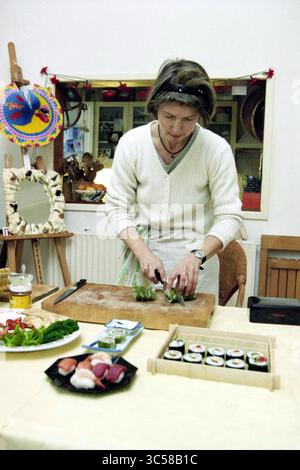 Mona schön Sushi Course, 22-02-2000 Whizgle News, Dutch Desk, Niederlande, 1950-2000 Eine Person bereitet Sushi in einer gemütlichen Küche geschickt zu, umgeben von frischen Zutaten und einem wunderschön angeordneten Teller mit verschiedenen Sushi-Brötchen und -Beilagen. Die Atmosphäre ist lebhaft, dekoriert mit bunten Kunsthandwerk im Hintergrund. Stockfoto