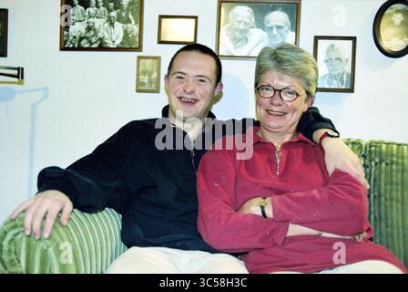 Behinderte Floris, Haarlem, Niederlande, 10-11-1999 Whizgle News, Dutch Desk, Niederlande, 1950-2000 Ein junger Mann mit fröhlichem Ausdruck sitzt neben einer lächelnden Frau, entspannt und bequem auf einer grünen Couch. Sie teilen einen warmen Moment zusammen, umgeben von gerahmten Bildern an der Wand hinter ihnen. Stockfoto