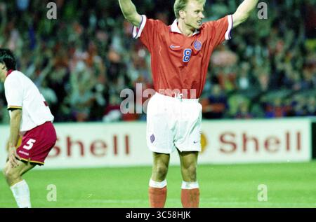 Qualifikationsspiel für die Fußball-Weltmeisterschaft 1998: Die Niederlande spielen gegen Belgien im de Kuip in Rotterdam und gewinnen 3:1., Rotterdam, 06-09-1997 Whizgle News, Dutch Desk, Niederlande, 1950-2000 Ein Fußballspieler feiert überschwänglich auf dem Spielfeld, trägt ein leuchtendes rotes Trikot mit der Nummer 8, während ein anderer Spieler im Hintergrund deprimiert erscheint. Die Atmosphäre ist aufgeladen und spiegelt die Intensität des Spiels wider. Stockfoto