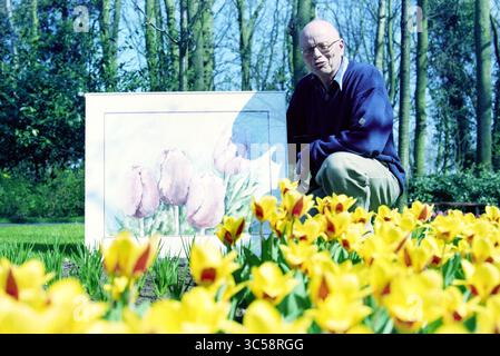 M. v. Nijnatten, Keukenhof, Lisse, 31-03-1997, Whizgle News, Dutch Desk, Niederlande, 1950-2000 Ein Mann kniet neben einem leuchtenden Tulpenbild, umgeben von einem Bett blühender gelber Blumen. Üppig grüne Bäume bieten eine ruhige Kulisse für die Szene. Stockfoto