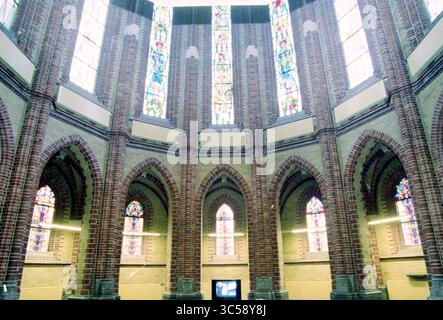 Sacred Heart Church, Apartments, Haarlem, Niederlande, 02-09-1998 Whizgle News, Dutch Desk, Niederlande, 1950-2000 Ein atemberaubender Innenraum mit hoch aufragenden Ziegelbögen und hohen, bunten Buntglasfenstern, die den Raum mit komplexen Mustern und Licht beleuchten. Das architektonische Design betont Pracht und ein Gefühl der Ruhe. Stockfoto