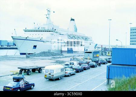 Seaways, beschäftigt mit Autos IJmuiden, IJmuiden, Niederlande, 31-07-1997, Whizgle News, Dutch Desk, Niederlande, 1950-2000 Eine große Fähre wird an einem Terminal angedockt, wobei Fahrzeuge im Vordergrund stehen. Fracht wird auf das Schiff geladen, während nahe gelegene Strukturen die geschäftige maritime Aktivität unterstützen. Stockfoto