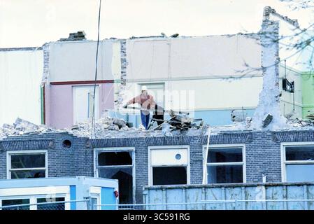 Abriss der Trinity High School, Haarlem, Zijlweg, Niederlande, 11-03-1998 Whizgle News, Dutch Desk, Niederlande, 1950-2000 Ein Bauarbeiter steht auf einem teilweise abgerissenen Gebäude und entfernt aktiv Schutt vom Dach, umgeben von Resten von Wänden und Bauwerken. Stockfoto