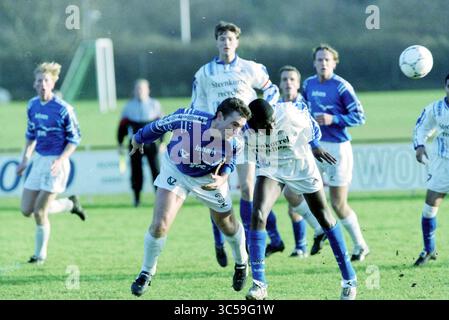 Fußball: Stormvogels - DWS, IJmuiden, Niederlande, 12-12-1998 Whizgle News, Dutch Desk, Niederlande, 1950-2000 Ein angespannter Moment auf dem Fußballfeld, als zwei Spieler zusammenstoßen und hart um die Kontrolle über den Ball kämpfen. Ein Spieler in einem blauen Trikot wird überrascht, während der andere in weiß seine Entschlossenheit zum Ausdruck bringt, während er in einer energiegeladenen Match-Atmosphäre um die Dominanz kämpft. Stockfoto