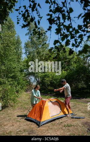 Kaukasische Männer und Frauen, die im Freien Zelt aufstellen. Stockfoto