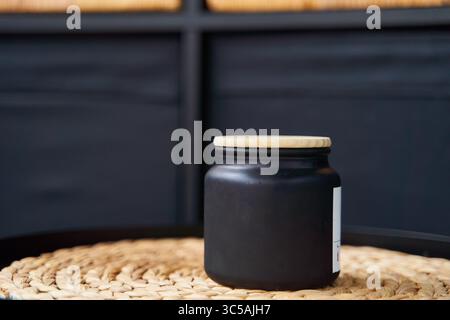 Stilvolles schwarzes Glas mit einem Holzdeckel für eine Kerze oder Creme Stockfoto