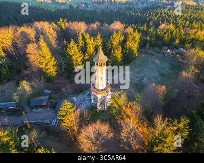Der Stepanka Aussichtsturm erwartet Sie im Morgenlicht inmitten des üppigen Grüns des Isergebirges. Die beschauliche Landschaft von Korenov bietet einen ruhigen Zufluchtsort in die Natur. Stockfoto