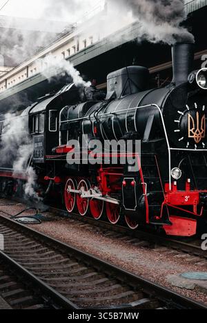 Old steam locomotive at the station. Three quarter front view of MAVAG steam engine idling near the station platform. Stockfoto