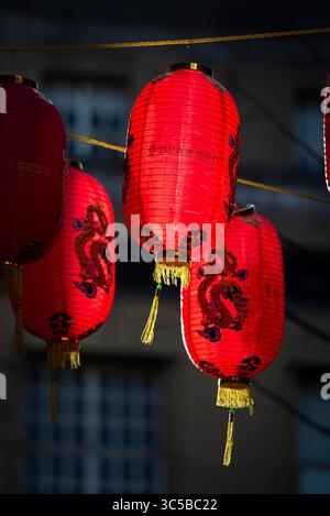 Nahaufnahme traditioneller chinesischer roter Laternen, die in Londons Chinatown hängen und während des chinesischen Neujahrs wunderschön mit komplizierten Drachenmotiven beleuchtet sind Stockfoto