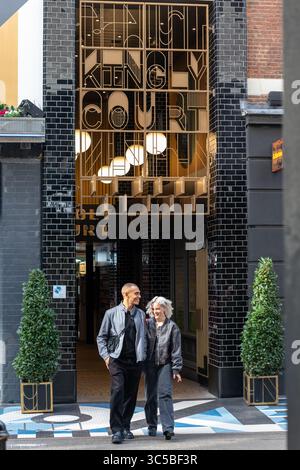 Ein Paar spaziert am Eingang zum Kingly Court vorbei, einem beliebten Einkaufs- und Restaurantziel in Soho, London, England. Stockfoto